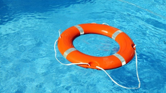 Gaiši zilā ūdenstilpnē oranžs glābšanas riņķis