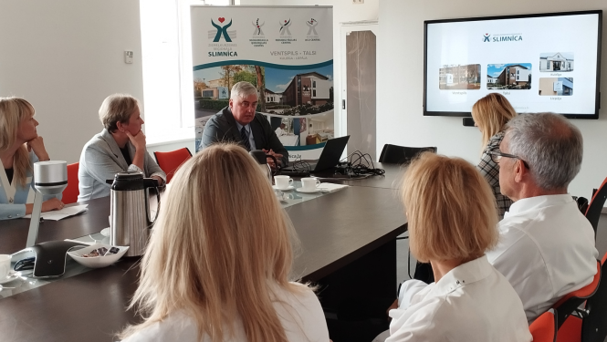 Ārstniecības personas sēd ap galdu.