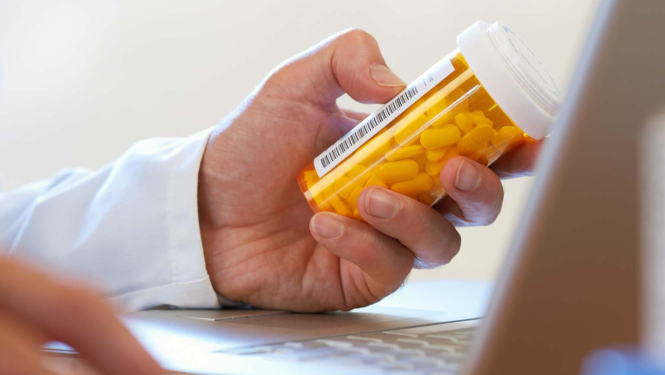 Ārsta roka ar medikamentu pudelīti