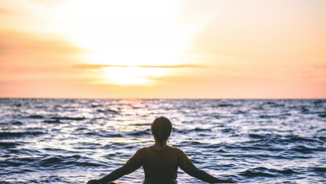 Cilvēks jūrā raugās uz saulrietu