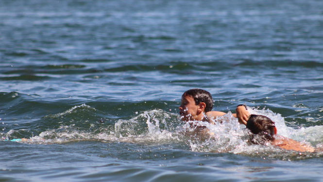 Zils jūras ūdens, ūdenī peld divi cilvēki