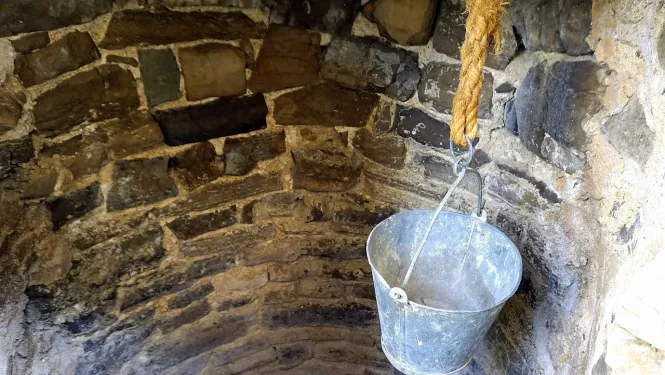 Akmens akas iekšpuse un spainis iesiets virvē 