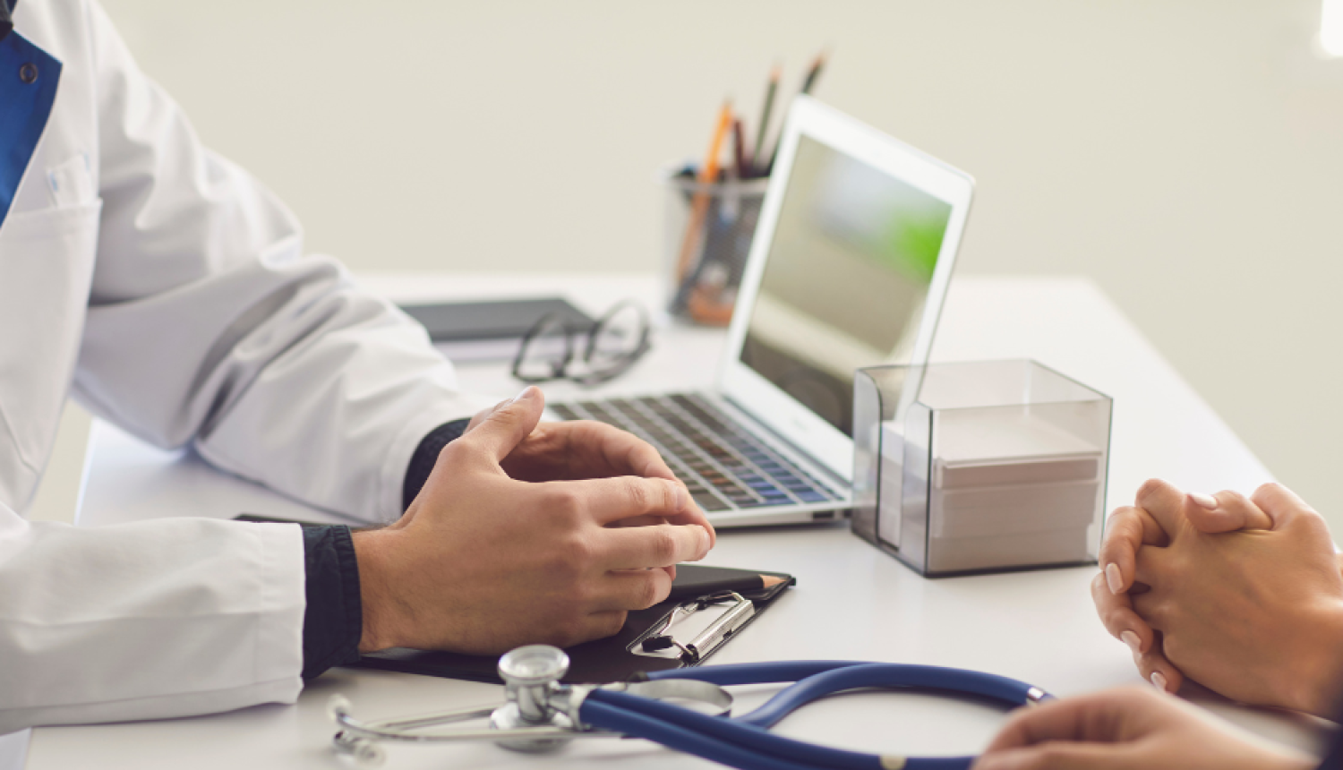 Ārsta un pacienta rokas uz galda