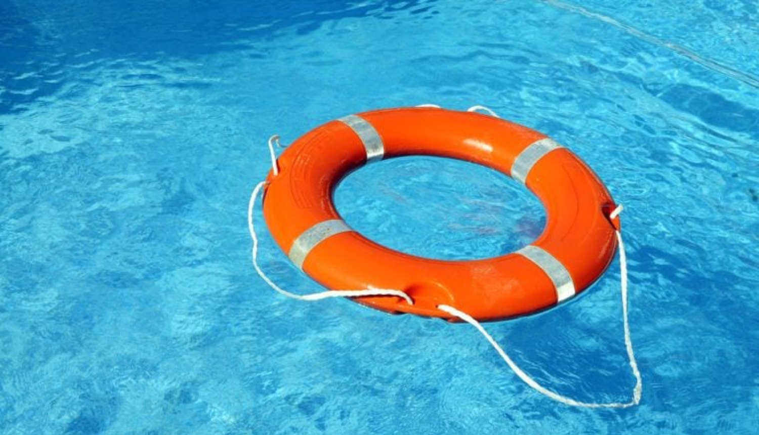 Gaiši zilā ūdenstilpnē oranžs glābšanas riņķis