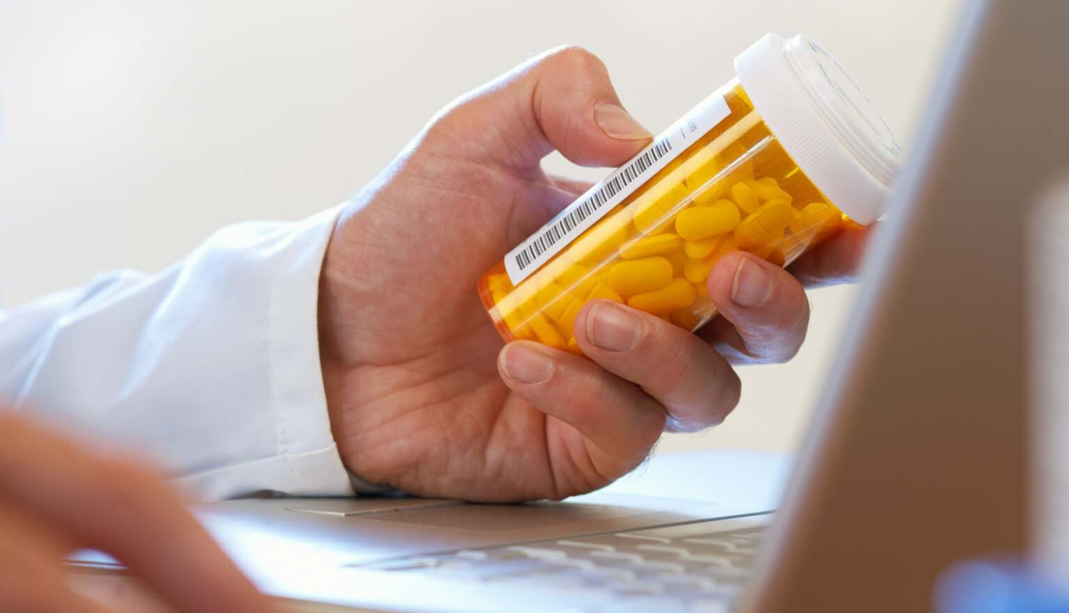 Ārsta roka ar medikamentu pudelīti