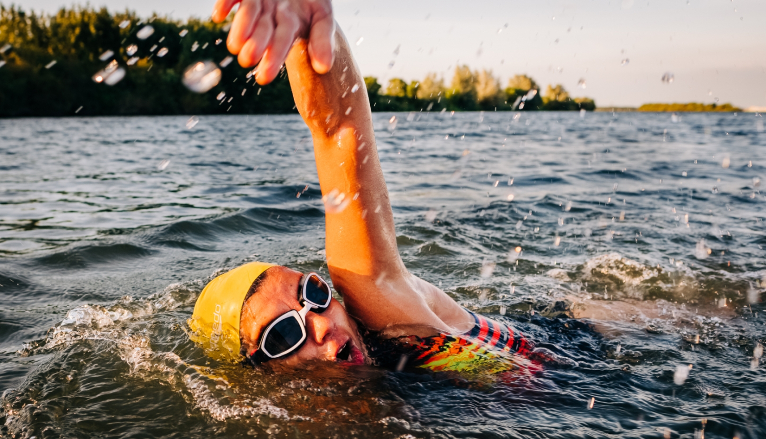 Ūdens tilpņē peldošs cilvēks dzeltenā peldcepurē