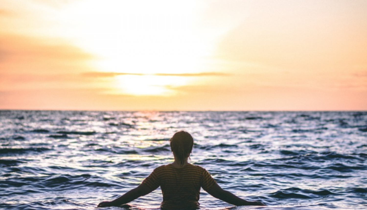 Cilvēks jūrā raugās uz saulrietu