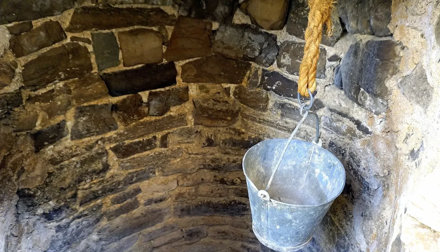 Akmens akas iekšpuse un spainis iesiets virvē 